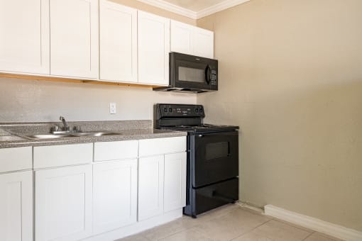 a kitchen with white cabinets and black appliances  at North Washington Apartments