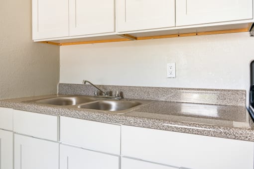 a kitchen with white cabinets and granite countertops at North Washington Apartments