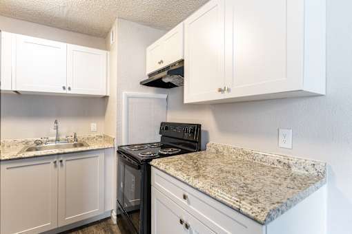 A kitchen with granite countertops and white cabinets.