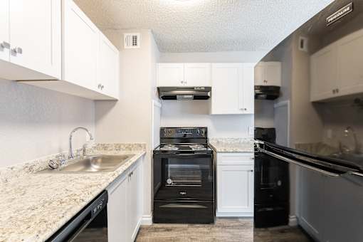 A kitchen with a black oven and white cabinets.