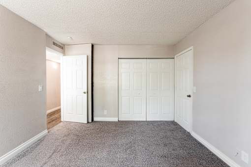 A room with white doors and carpeted floor.