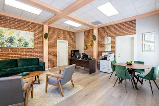 A living room with a green couch and a dining table with chairs.