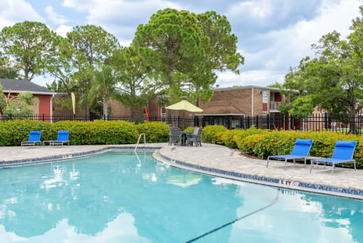 swimming pool with patio table and lounge chairs at Timberfalls Apartments