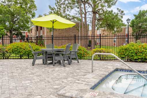 A patio with a table, chairs, and a pool.