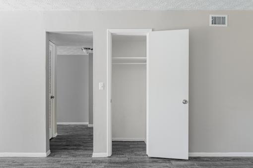 A white door is open to a room with a white wall and a vent.