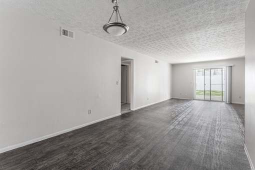 A large empty room with a wooden floor and a hanging light fixture.