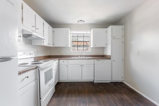 a kitchen with white appliances and white cabinets at Jacksonville Heights Apartments