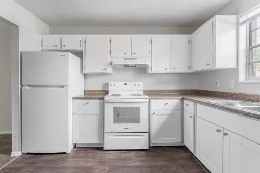 a kitchen with white cabinets and appliances at Jacksonville Heights Apartments