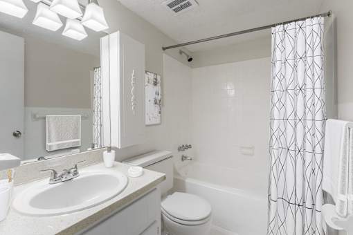 A white bathroom with a toilet, sink, and shower.
