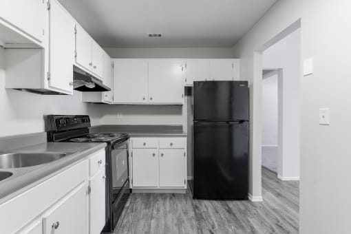 a kitchen with white cabinets and black appliances at Jacksonville Heights Apartments