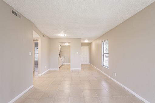 A spacious room with tiled flooring and white walls.