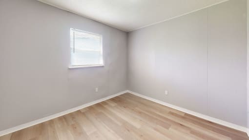 a bedroom with hardwood floors and grey walls