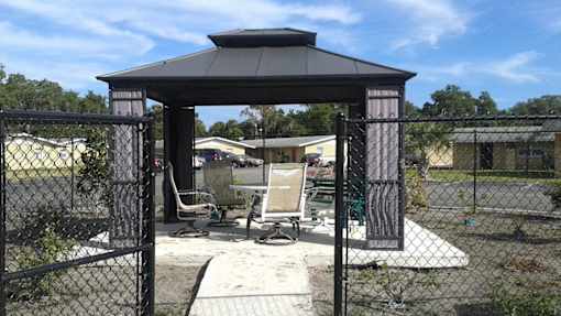 A gazebo with a black roof is surrounded by a black fence.