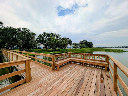 A wooden deck overlooks a body of water with a green landscape in the background.