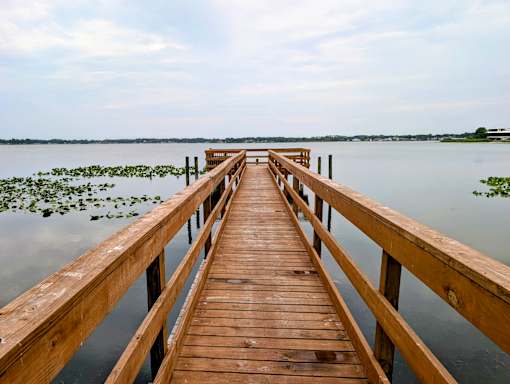 A wooden pier extends into a calm body of water.