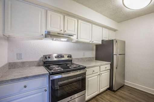 A kitchen with white cabinets and a stainless steel refrigerator.