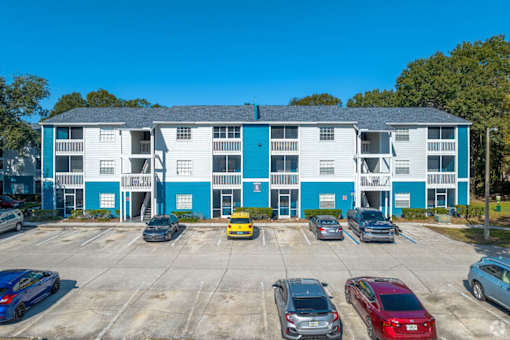 A parking lot with cars and a building with blue and white walls.