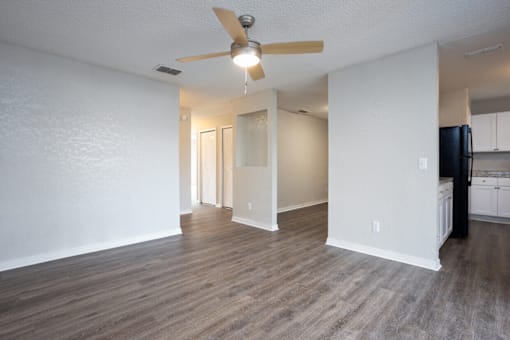 A room with a ceiling fan and wooden flooring.