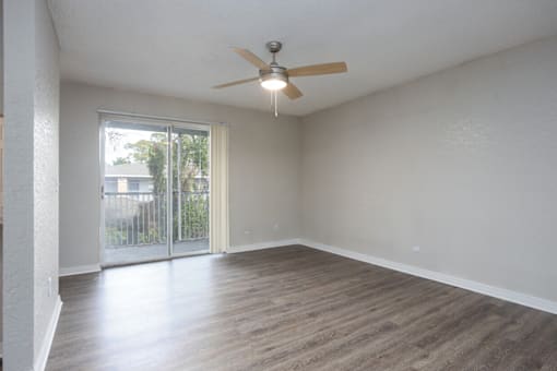A room with a ceiling fan and sliding glass doors.