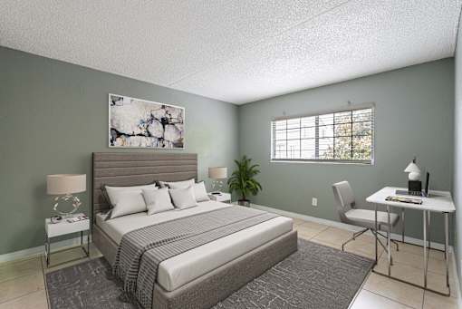 A bedroom with a large bed, a desk, and a chair.