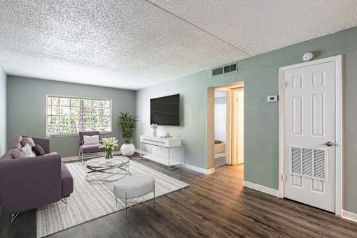 A living room with a purple couch and a flat screen TV.