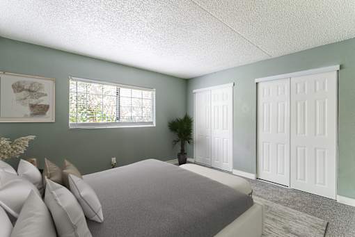 A bedroom with a bed, pillows, and a window.