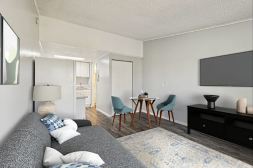 A living room with a grey couch, a wooden table, and a television on the wall.