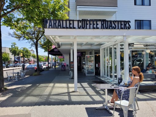 a woman sitting at a table in front of a coffee shop