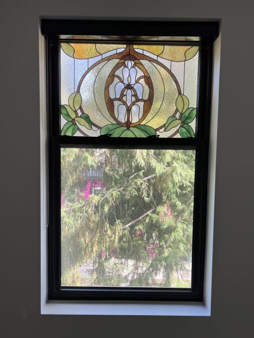 a stained glass window with a view of a weeping willow tree