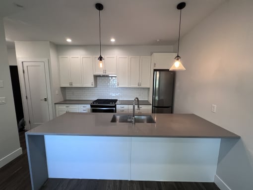 a kitchen with white cabinets and a gray counter top