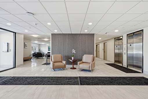 A spacious office lobby with two chairs and a coffee table.