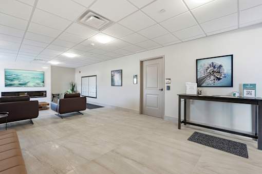 A reception area with a desk, chairs, and pictures on the wall.