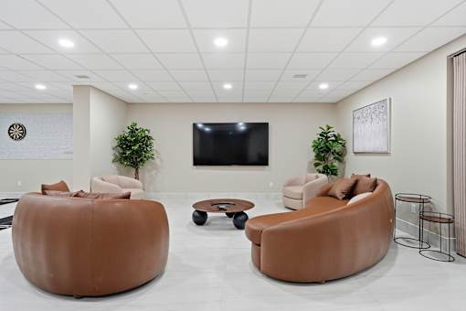 A modern living room with a brown leather sofa and a flat screen TV mounted on the wall.