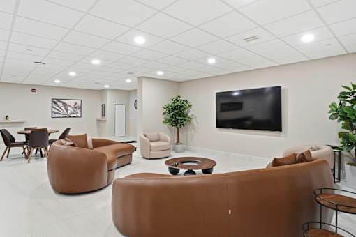 A living room with brown leather furniture and a flat screen TV mounted on the wall.