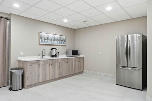 A kitchen with a refrigerator, sink, and a picture on the wall.
