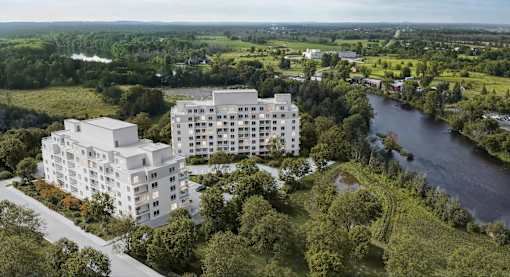 A modern white building is situated by a river in a green landscape.