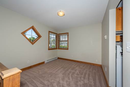 an empty living room with two windows and a kitchenette