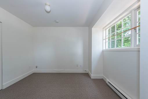 a small bedroom with a large window and white walls