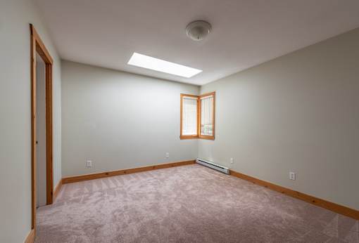 an empty room with a skylight and a wooden door