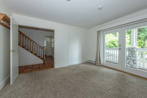 a bedroom with a sliding glass door and a staircase in the background