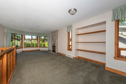 a large living room with carpeted flooring and a large window with a view of the