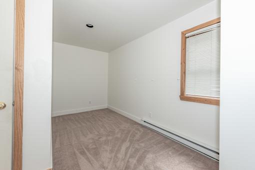 a bedroom with white walls and a wooden floor