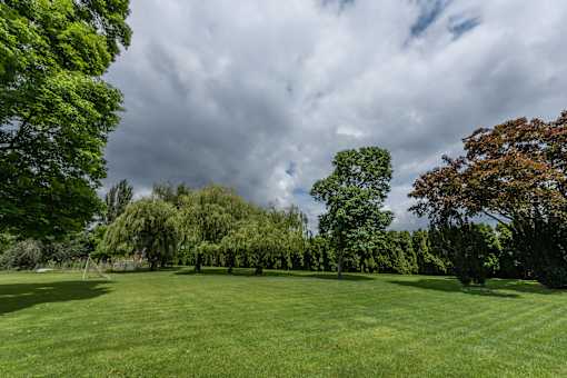 a large grassy field with trees in the background