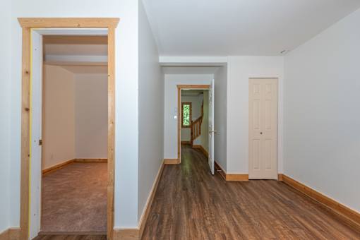 a bedroom with hardwood floors and white walls