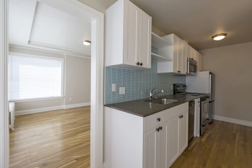 a kitchen with white cabinets and a sink and a window
