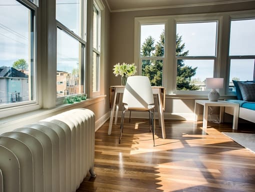 a living room with a radiator and a table with a chair