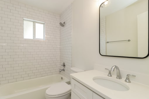 a bathroom with white tiles and a white sink and toilet
