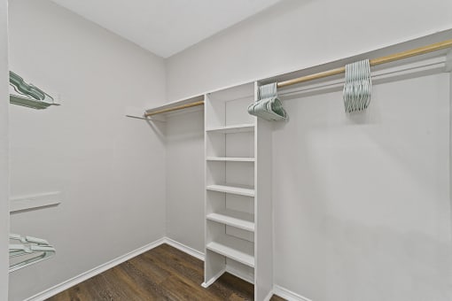 a walk in closet with white shelves and a mirrored closet door at Lakeside Apartments, Dallas, TX