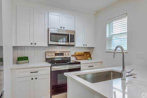 A kitchen with white cabinets and a stove top oven.