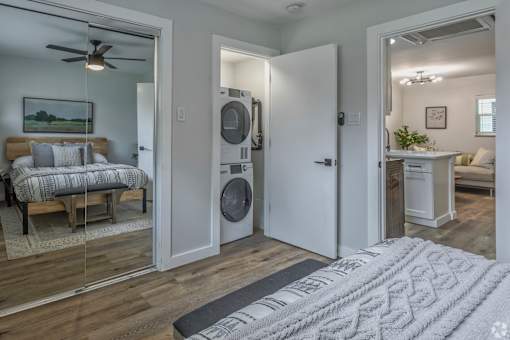 A bedroom with a washer and dryer in the doorway.